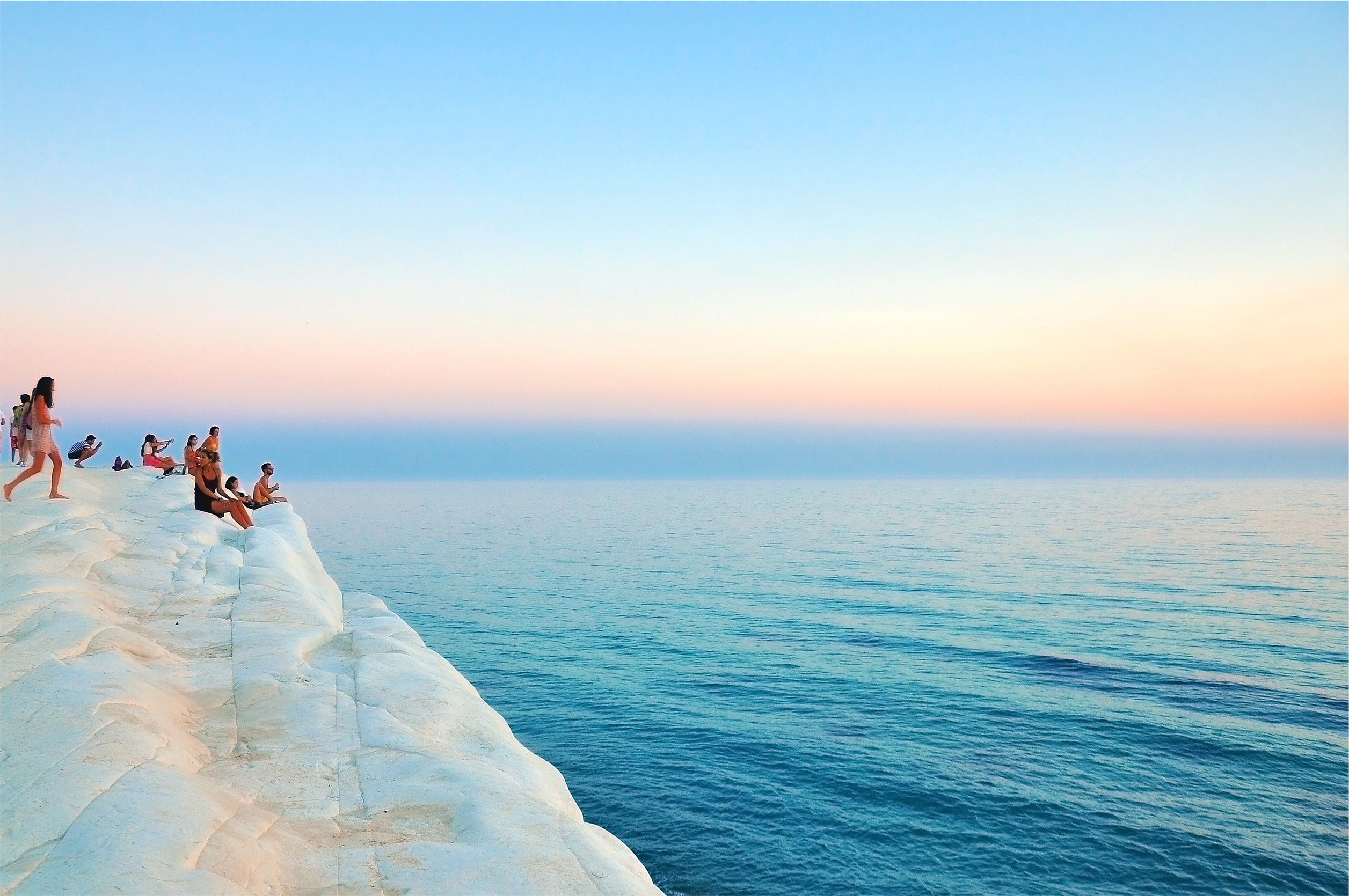 Group of People Sitting on a Coastal Cliff